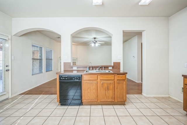 kitchen featuring a wealth of natural light, sink, light hardwood / wood-style flooring, and black dishwasher