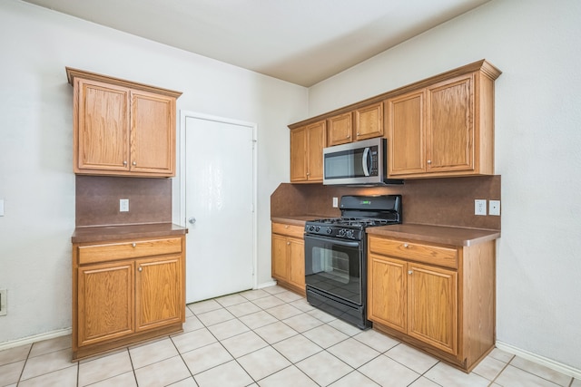 kitchen featuring light tile patterned flooring, black gas range oven, and tasteful backsplash