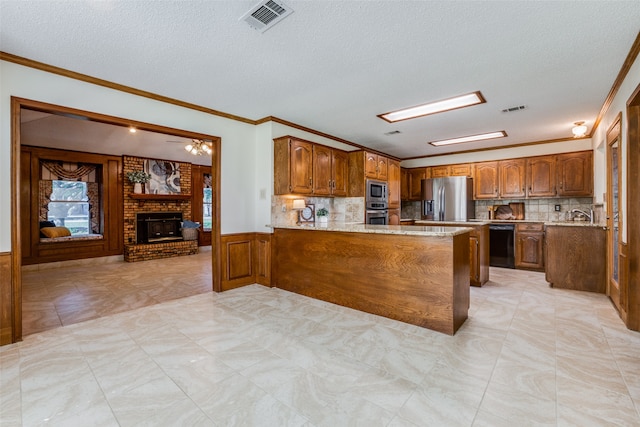 kitchen with stainless steel appliances, ornamental molding, a fireplace, and kitchen peninsula