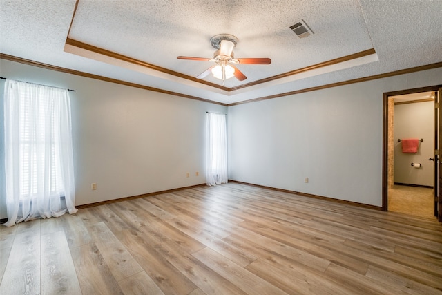 unfurnished room featuring ornamental molding, a raised ceiling, light hardwood / wood-style floors, and a textured ceiling