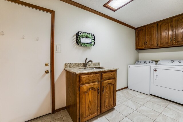 washroom featuring light tile patterned flooring, crown molding, cabinets, sink, and independent washer and dryer