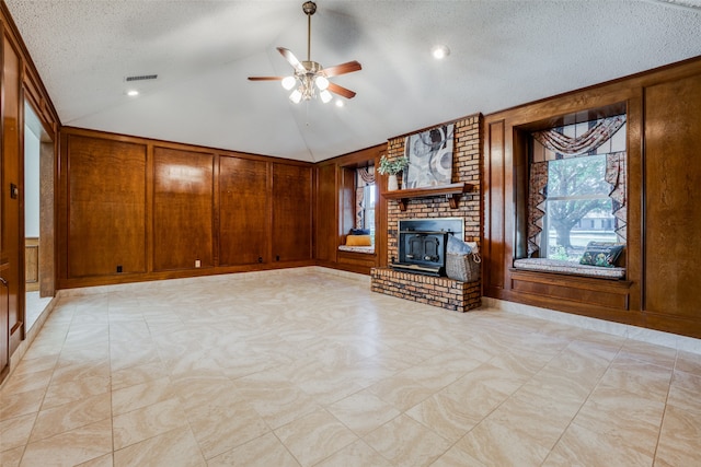 unfurnished living room with wooden walls, vaulted ceiling, and a textured ceiling