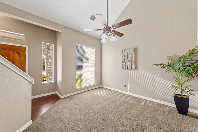 empty room featuring ceiling fan, wood-type flooring, a textured ceiling, and vaulted ceiling