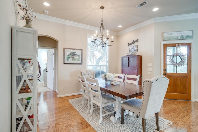 dining room featuring crown molding, a chandelier, plenty of natural light, and light hardwood / wood-style floors