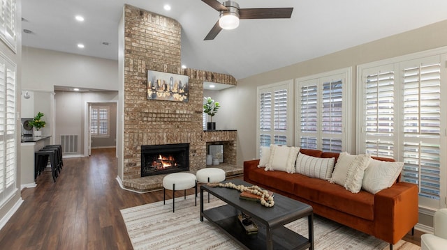 living room with a fireplace, hardwood / wood-style floors, high vaulted ceiling, and ceiling fan