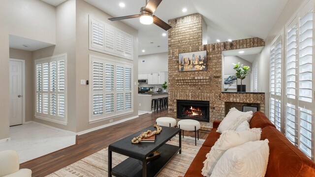 living room with high vaulted ceiling, ceiling fan, wood-type flooring, and a wealth of natural light