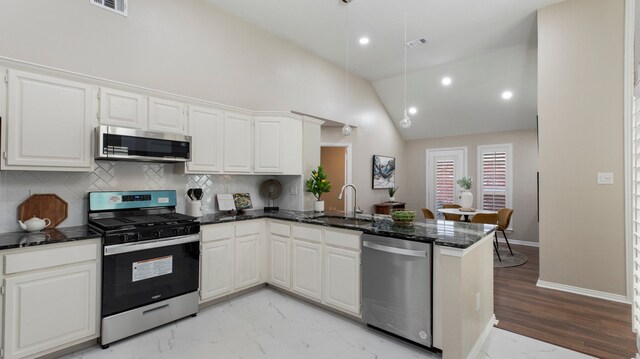 kitchen featuring kitchen peninsula, stainless steel appliances, sink, high vaulted ceiling, and white cabinets