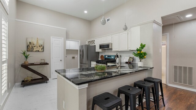 kitchen with stainless steel appliances, a kitchen breakfast bar, kitchen peninsula, pendant lighting, and white cabinets