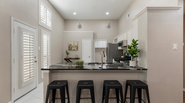 kitchen with sink, stainless steel appliances, white cabinetry, and dark stone countertops