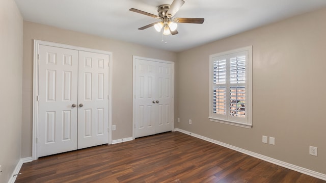 unfurnished bedroom featuring ceiling fan, dark hardwood / wood-style floors, and two closets