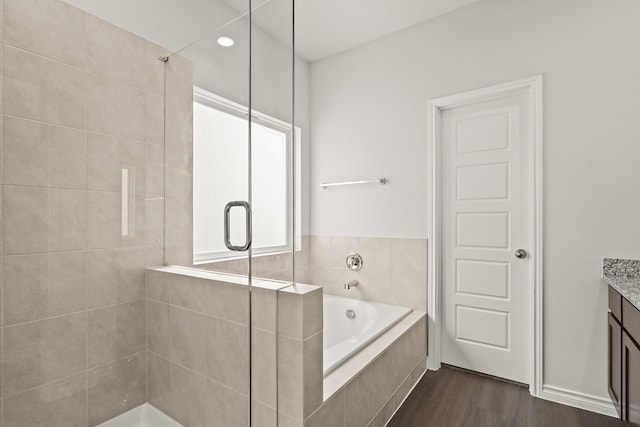 bathroom featuring plus walk in shower, hardwood / wood-style floors, and vanity