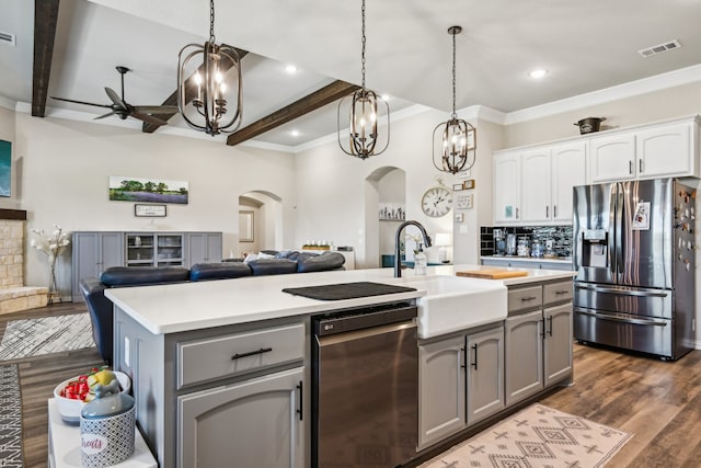 kitchen with dark hardwood / wood-style flooring, stainless steel appliances, beam ceiling, a center island with sink, and white cabinetry