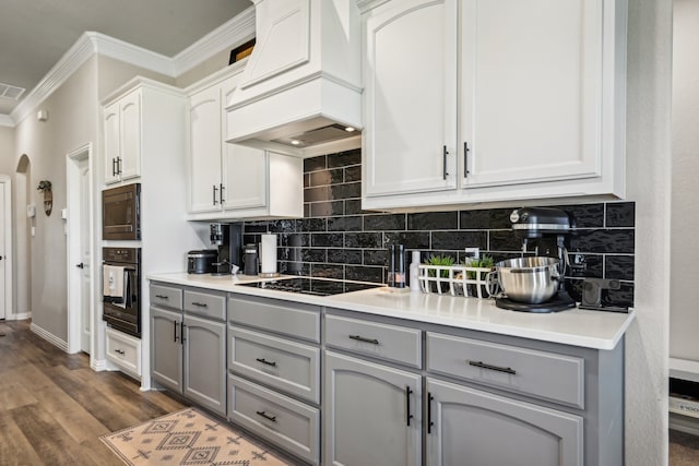 kitchen featuring custom range hood, backsplash, gray cabinets, and black appliances