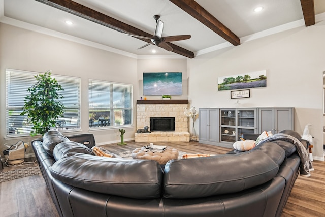 living room featuring ornamental molding, ceiling fan, beam ceiling, a fireplace, and hardwood / wood-style floors