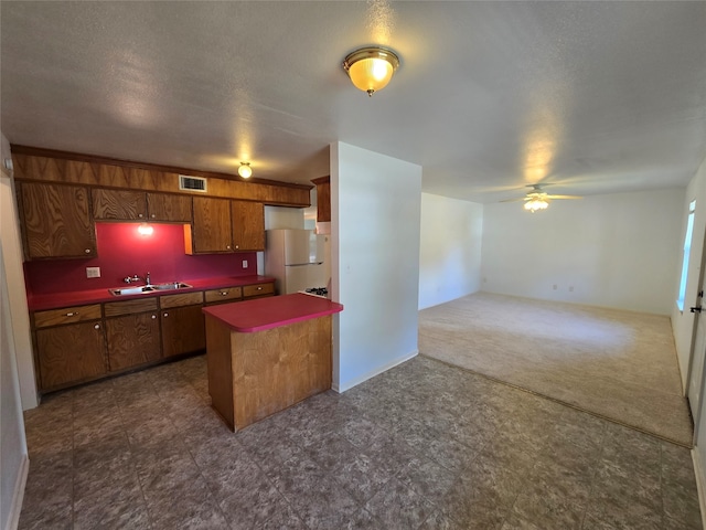 kitchen featuring ceiling fan, a textured ceiling, sink, and white refrigerator