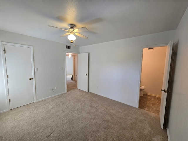 unfurnished bedroom featuring light colored carpet, ceiling fan, and ensuite bathroom