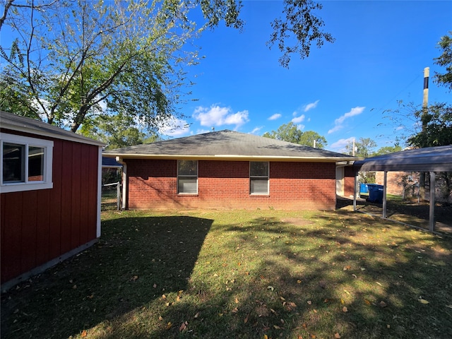 back of house with a storage unit, a yard, and a carport