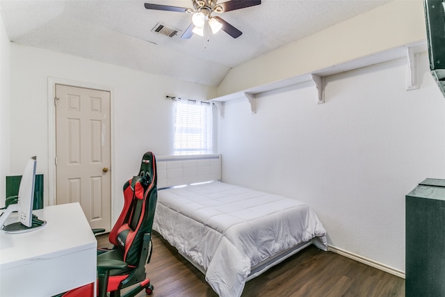 bedroom with a textured ceiling, dark wood-type flooring, ceiling fan, and vaulted ceiling