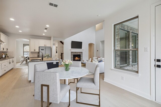 dining room featuring a stone fireplace, light wood-type flooring, and a healthy amount of sunlight