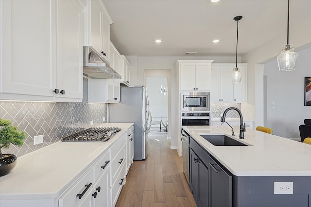 kitchen featuring stainless steel appliances, sink, pendant lighting, light hardwood / wood-style floors, and white cabinetry