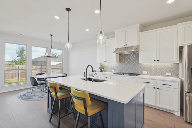 kitchen featuring white cabinets, pendant lighting, and an island with sink