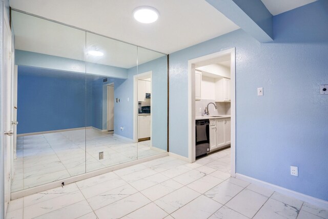 spare room featuring marble finish floor, baseboards, and a sink