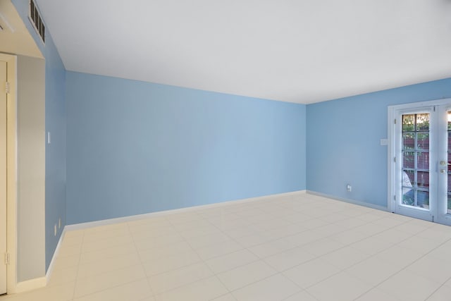 empty room featuring french doors, tile patterned flooring, visible vents, and baseboards