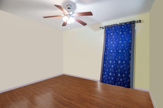 unfurnished room featuring a ceiling fan, baseboards, and wood finished floors