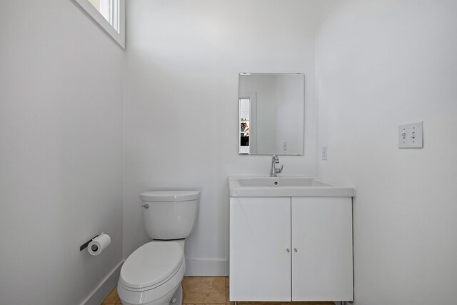 bathroom with toilet, vanity, and tile patterned floors