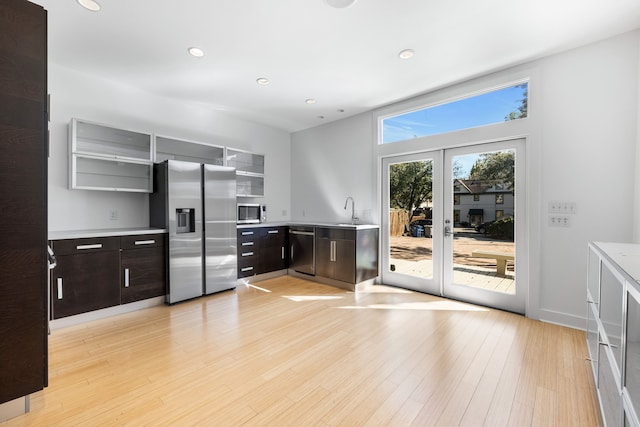 kitchen with dark brown cabinetry, stainless steel appliances, sink, and light hardwood / wood-style flooring