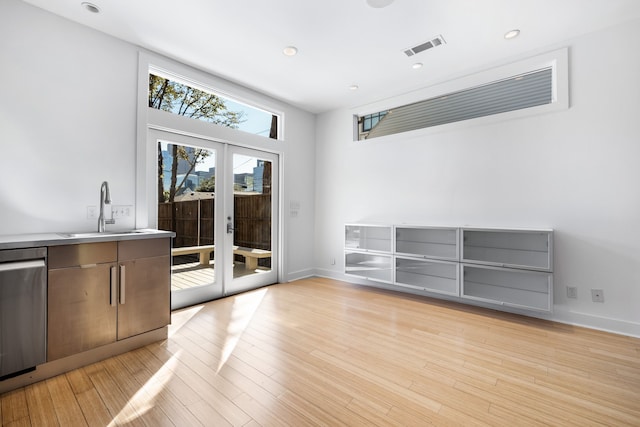 interior space featuring light hardwood / wood-style floors, a high ceiling, sink, and french doors