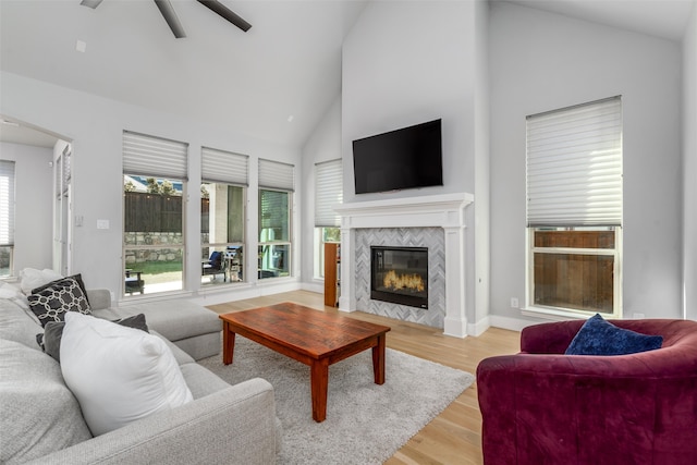 living room featuring high vaulted ceiling, light hardwood / wood-style flooring, ceiling fan, and a fireplace