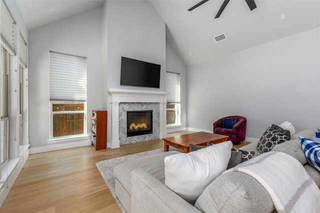 living room featuring a tiled fireplace, high vaulted ceiling, light hardwood / wood-style flooring, and ceiling fan