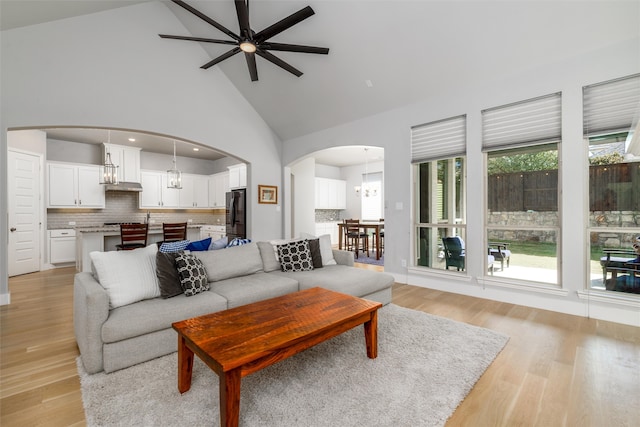 living room with high vaulted ceiling, plenty of natural light, ceiling fan, and light hardwood / wood-style flooring