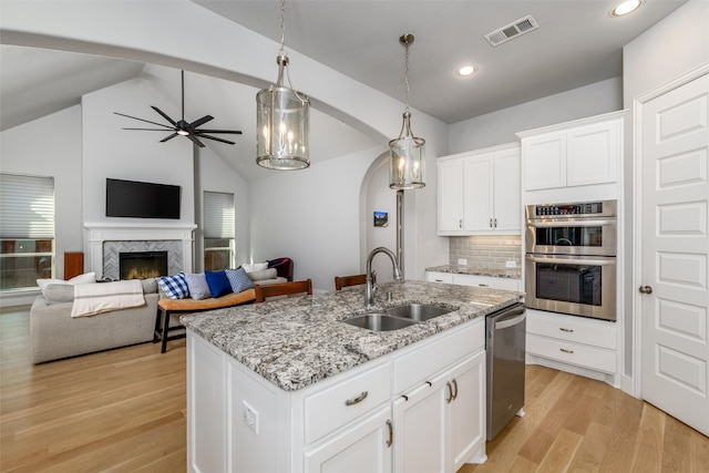 kitchen featuring appliances with stainless steel finishes, white cabinetry, lofted ceiling, and sink