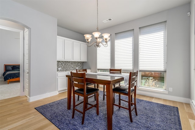 dining space featuring light wood-type flooring and a chandelier