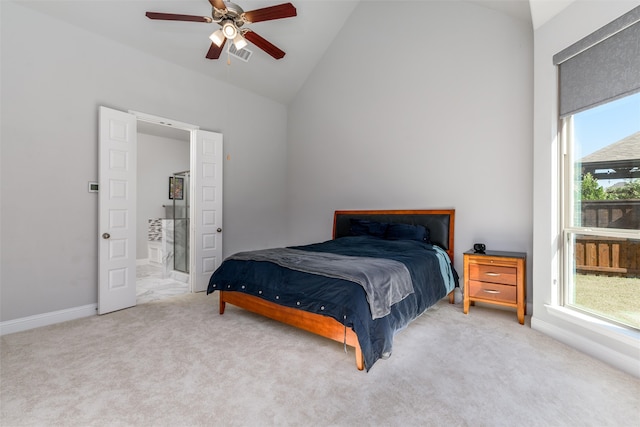 bedroom featuring high vaulted ceiling, light colored carpet, ceiling fan, and ensuite bath