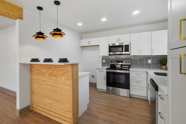 kitchen with stainless steel appliances, white cabinetry, decorative light fixtures, and dark hardwood / wood-style flooring