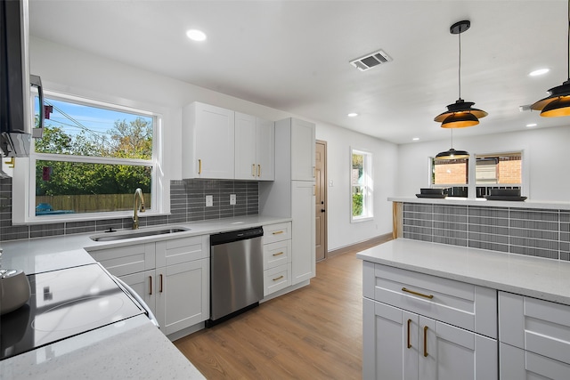 kitchen featuring stainless steel dishwasher, a wealth of natural light, hanging light fixtures, and sink