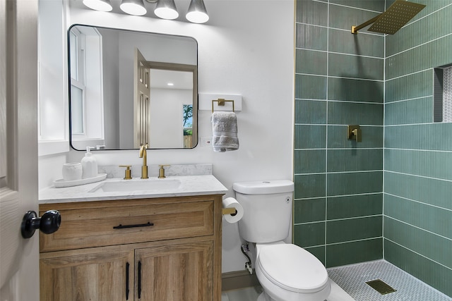 bathroom with toilet, vanity, and a tile shower