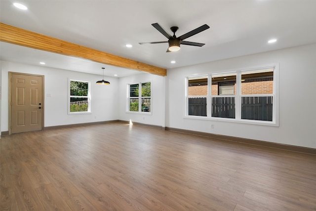 unfurnished living room featuring wood-type flooring, ceiling fan, and beam ceiling