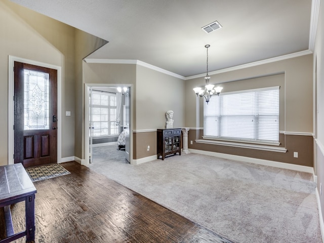 entryway with a chandelier, crown molding, and carpet