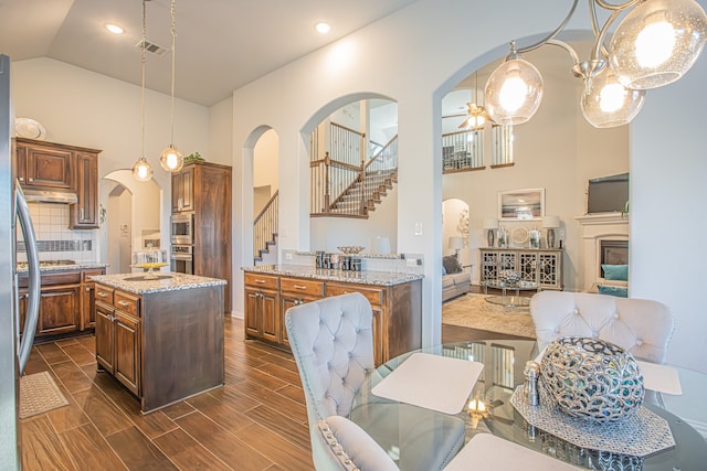 kitchen featuring light stone countertops, tasteful backsplash, dark hardwood / wood-style floors, a kitchen island, and hanging light fixtures