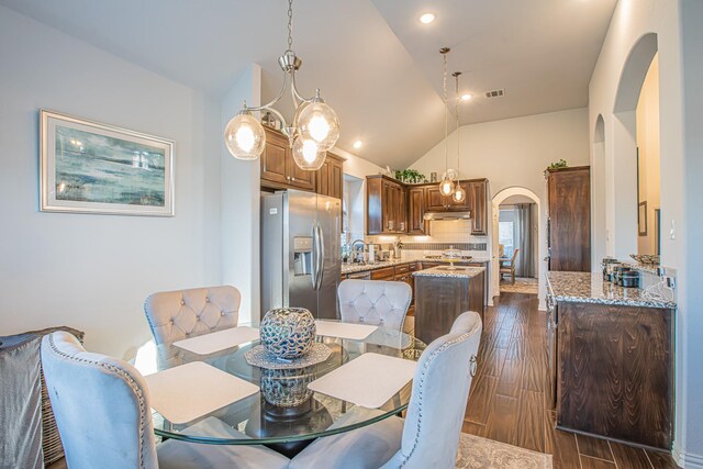 dining room with high vaulted ceiling, dark hardwood / wood-style floors, and an inviting chandelier