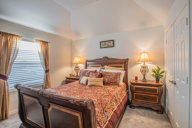 carpeted bedroom with vaulted ceiling and a closet