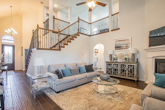 living room featuring high vaulted ceiling, dark wood-type flooring, and ceiling fan with notable chandelier