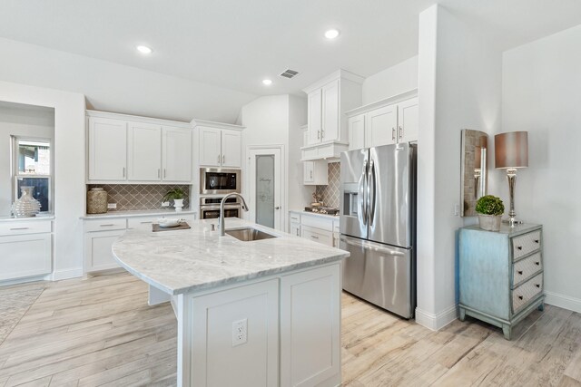 kitchen featuring white cabinetry, light wood-type flooring, appliances with stainless steel finishes, and a center island with sink