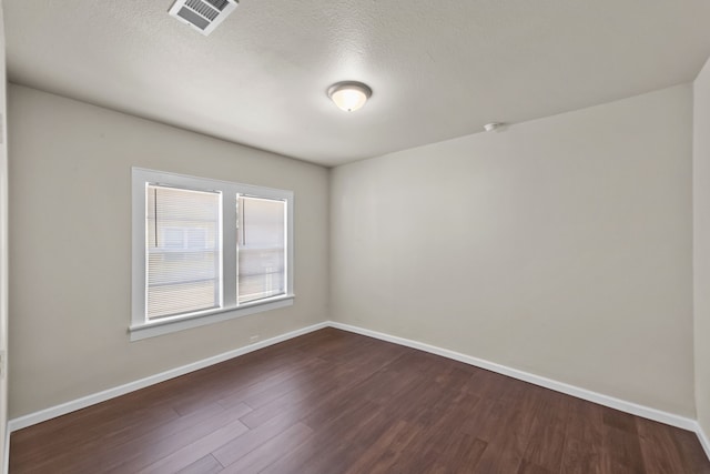 empty room featuring a textured ceiling and dark hardwood / wood-style flooring