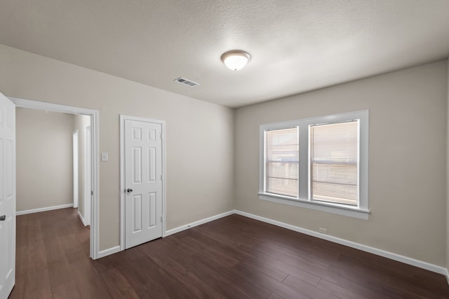 spare room featuring a textured ceiling and dark hardwood / wood-style floors