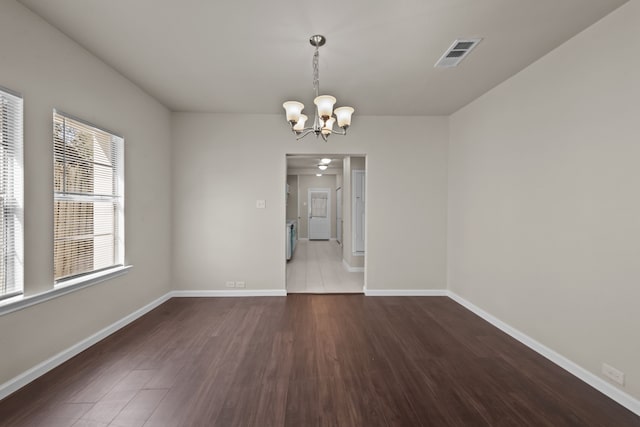 unfurnished dining area featuring dark wood-type flooring and a notable chandelier